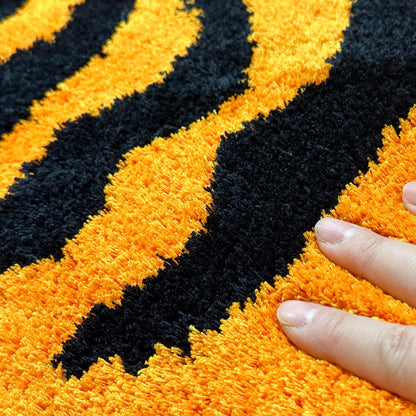 Feblilac Orange and Black Tiger tufted bath mat in front of a bathroom vanity with fresh towels