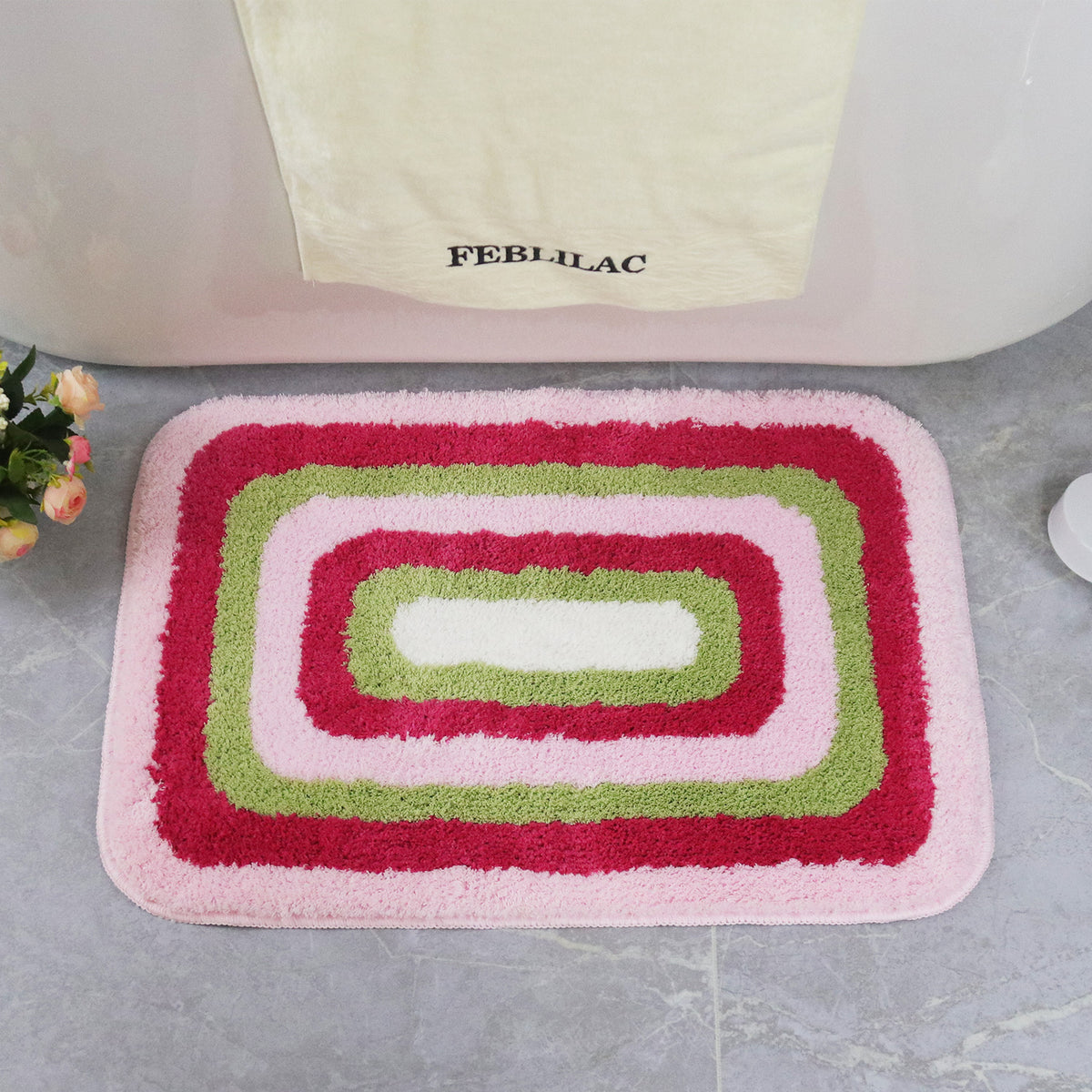 Feblilac Red Green and White Greek Key tufted bath mat in front of a bathroom vanity with fresh towels