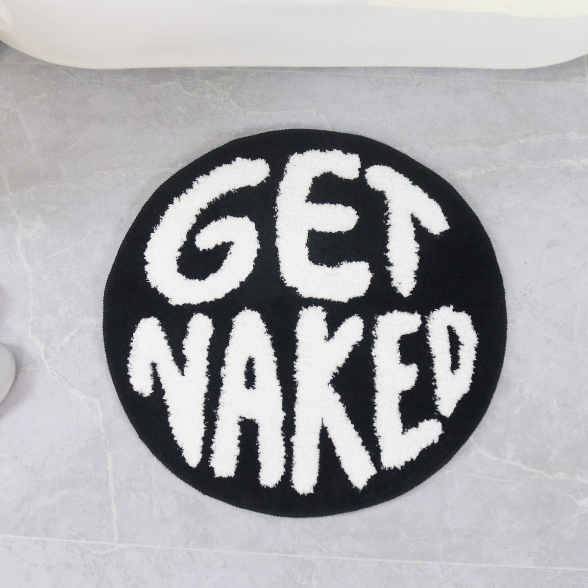 Feblilac Get Naked tufted bath mat in front of a bathroom vanity with fresh towels