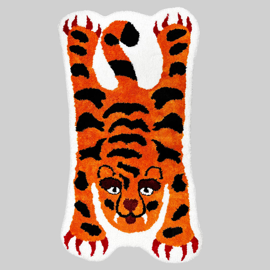 Feblilac Orange and Black Tiger tufted bath mat on a wood floor next to a soaking tub