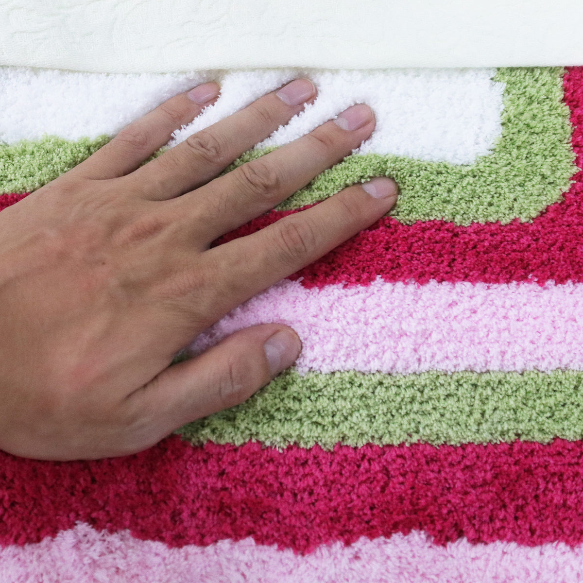 Feblilac Red Green and White Greek Key tufted bath mat in a sunny bathroom with a potted plant