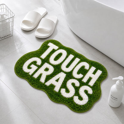 TOUCH GRASS green tufted rug by a bathtub with white slippers and towel basket
