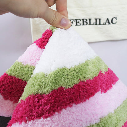 Feblilac Red Green and White Greek Key tufted bath mat by the sink with slippers and a towel basket