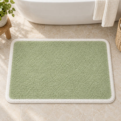 Feblilac Green with White Border tufted bath mat in front of a bathroom vanity with fresh towels