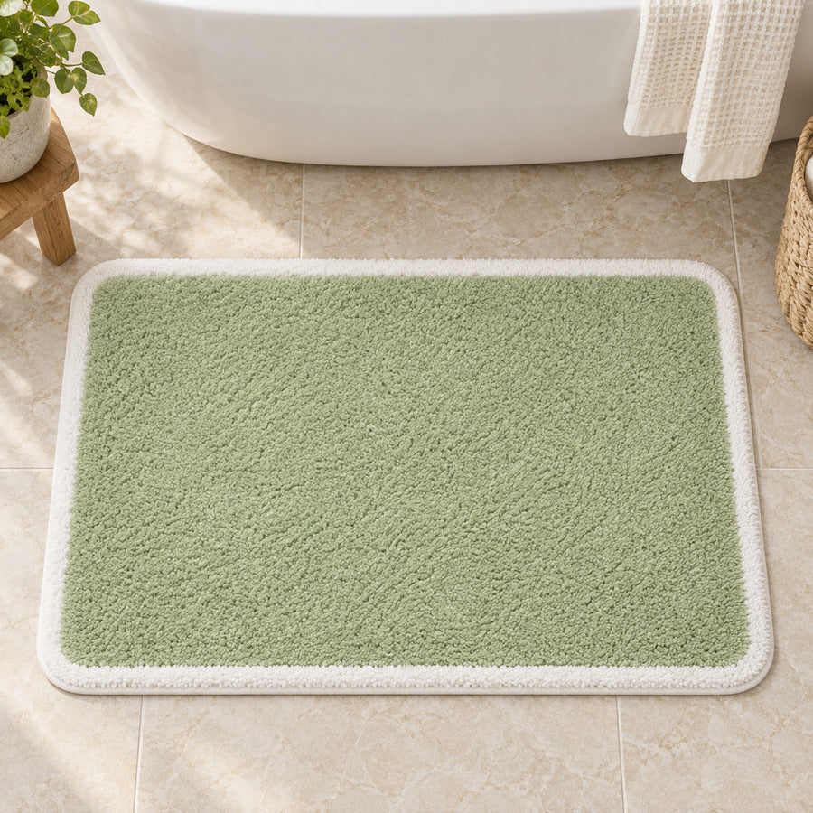 Feblilac Green with White Border tufted bath mat in front of a bathroom vanity with fresh towels