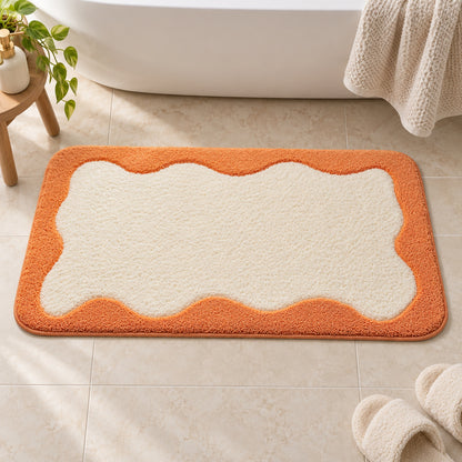 Feblilac Orange Wavy Border tufted bath mat in front of the bathtub in natural light
