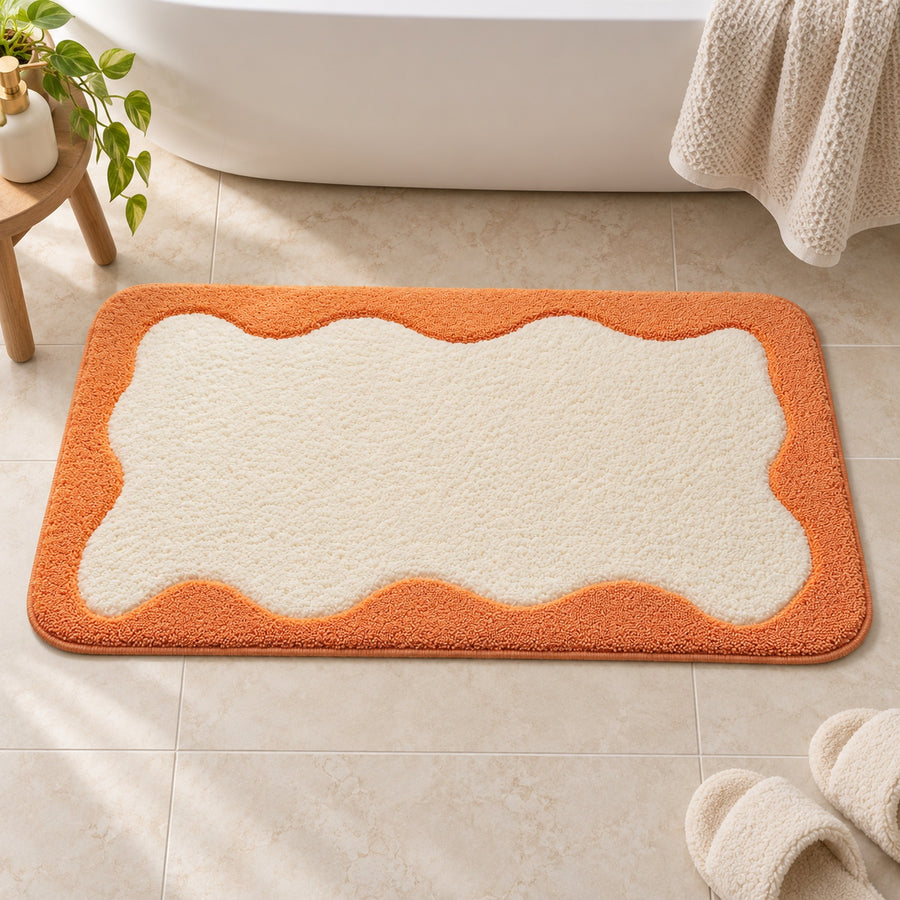 Feblilac Orange Wavy Border tufted bath mat in front of the bathtub in natural light