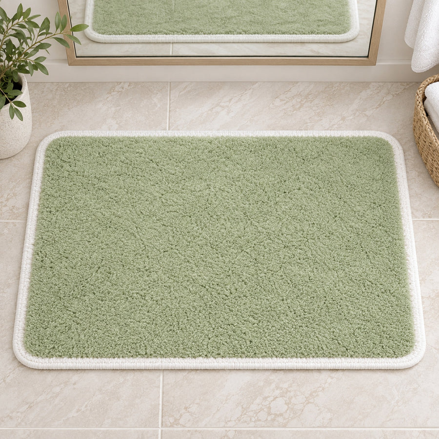 Feblilac Green with White Border tufted bath mat on a wood floor next to a soaking tub