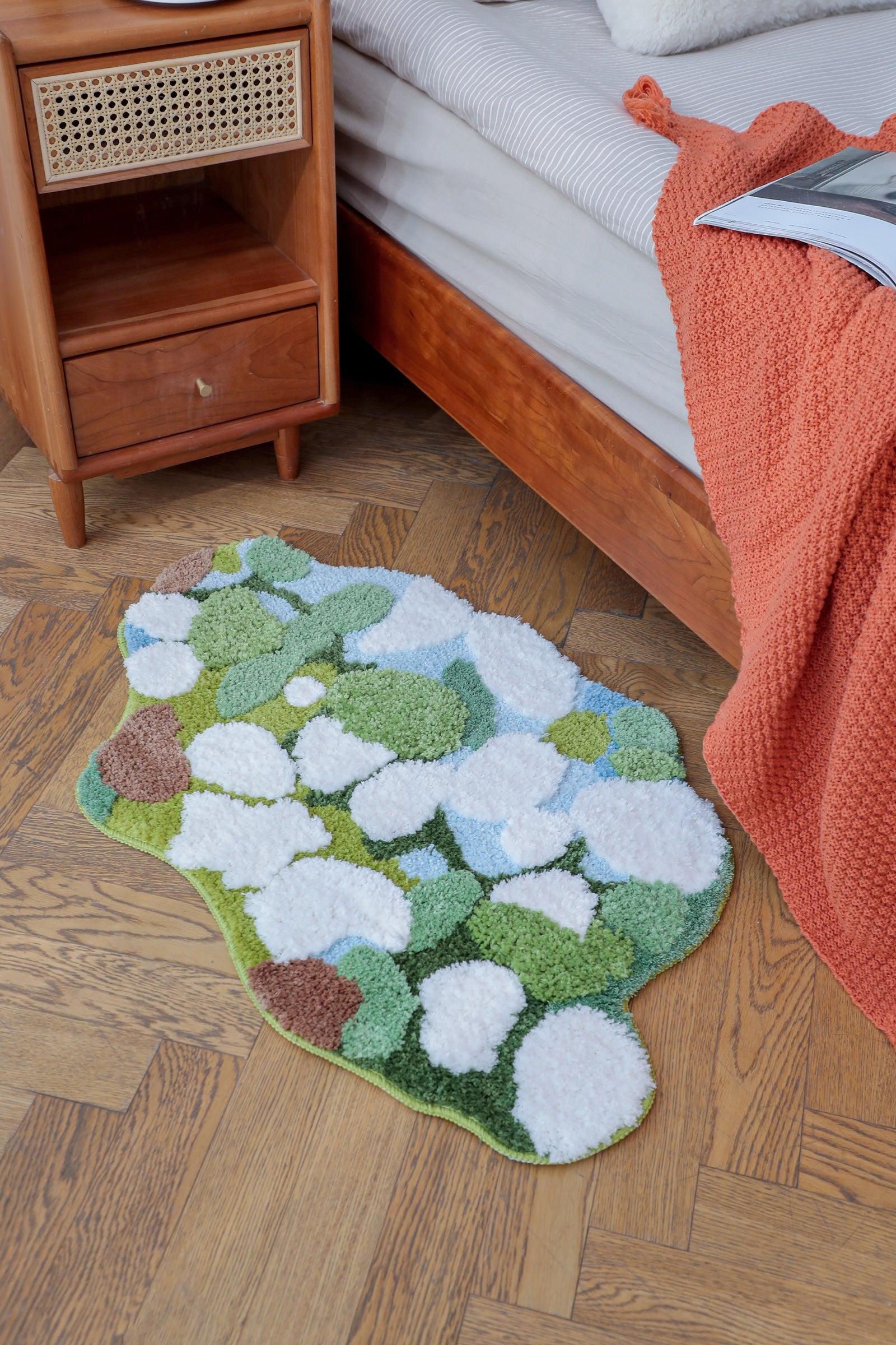 Green cloud-shaped Feblilac mat beside a bed in a real bedroom
